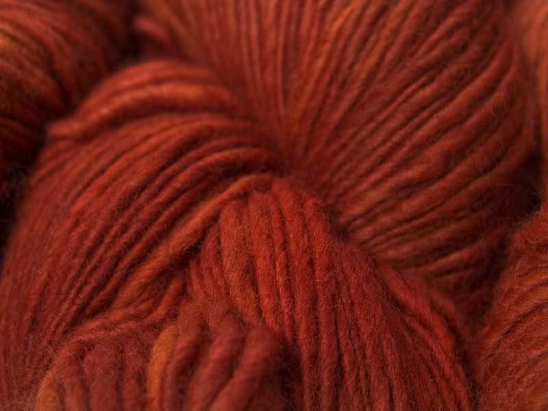 Semi-solid fiery orange Corriedale thick and thin slub yarn. Hand-dyed by Triskelion Yarn.