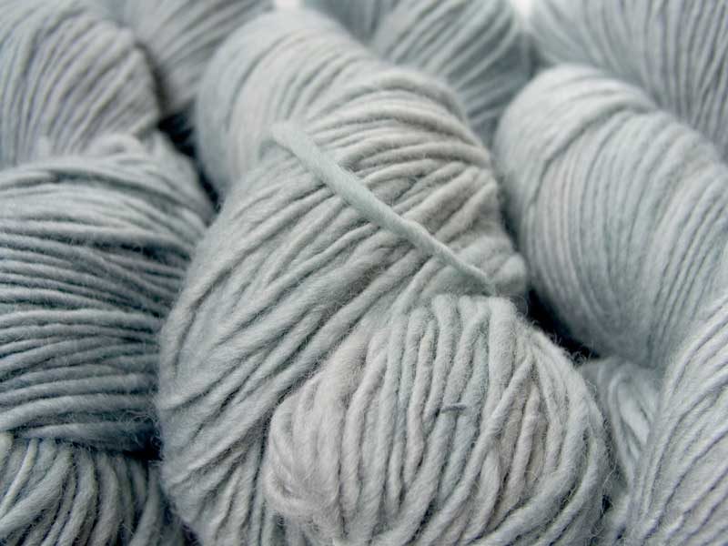 Semi-solid to solid bright bluish grey Corriedale thick and thin slub yarn. Hand-dyed by Triskelion Yarn.