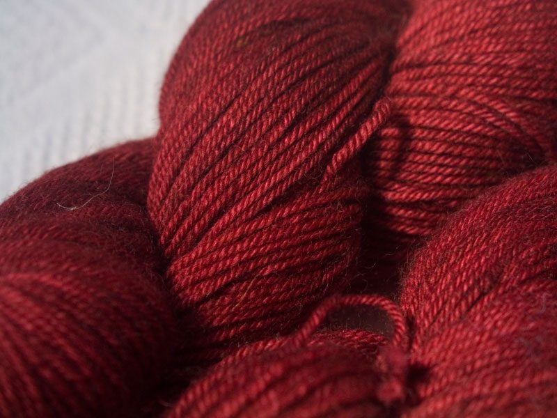 Semi-solid deep red superwash Bluefaced Leicester (BFL) double knit yarn. Hand-dyed by Triskelion Yarn