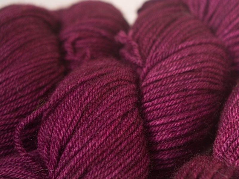 Semi-solid deep red-violet superwash Bluefaced Leicester (BFL) double knit yarn. Hand-dyed by Triskelion Yarn