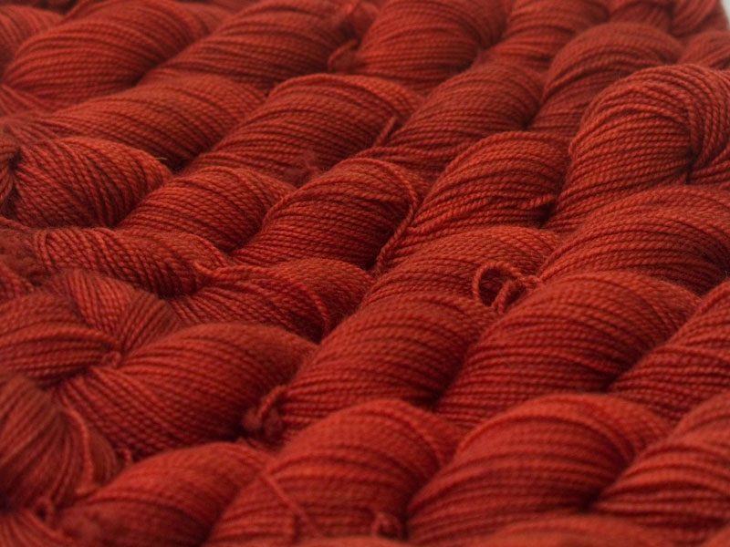 Mid-toned red superwash Bluefaced Leicester (BFL) 4-ply/fingering/sock yarn. Hand-dyed by Triskelion Yarn