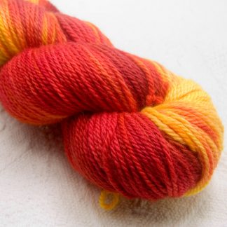 Nectarine - a mix of fruity reds over a warm peachy yellow base Bluefaced Leicester worsted weight yarn hand-dyed by Triskelion Yarn